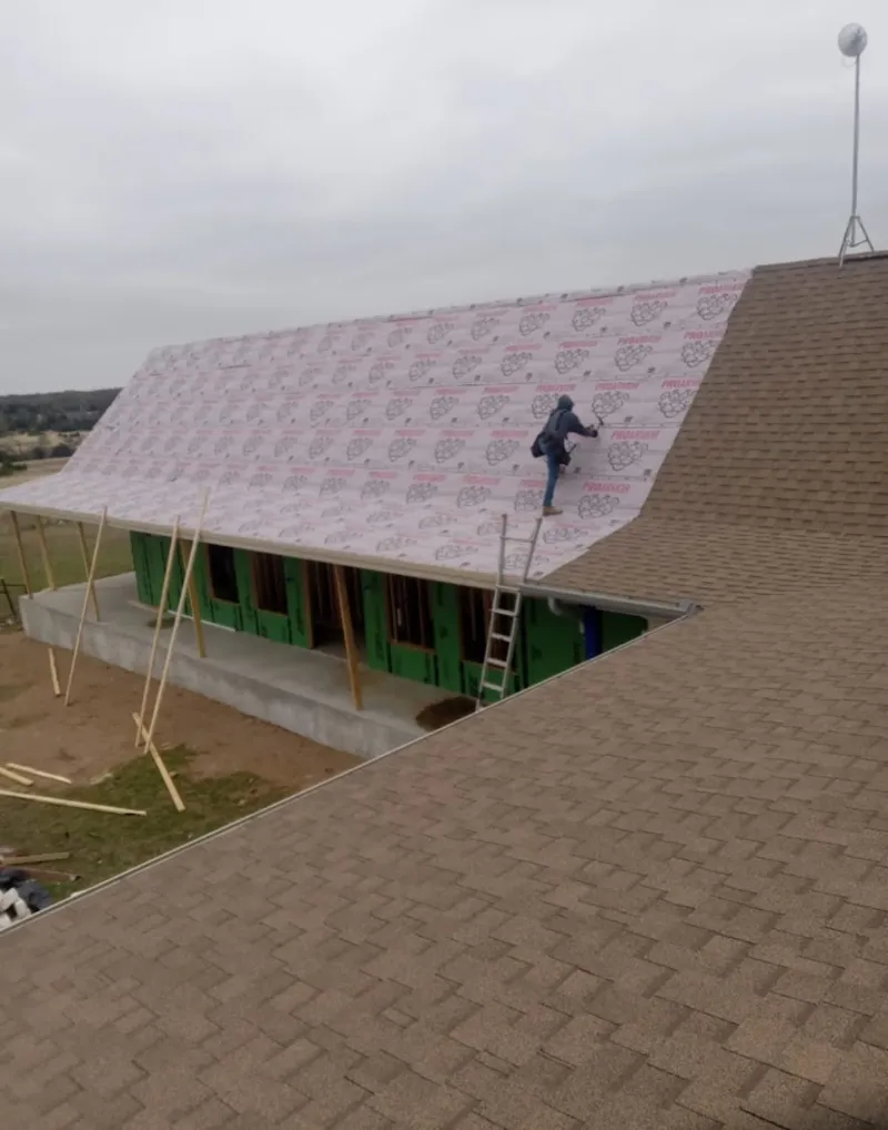 Worker preparing underlayment for a metal roof installation in Sheffield